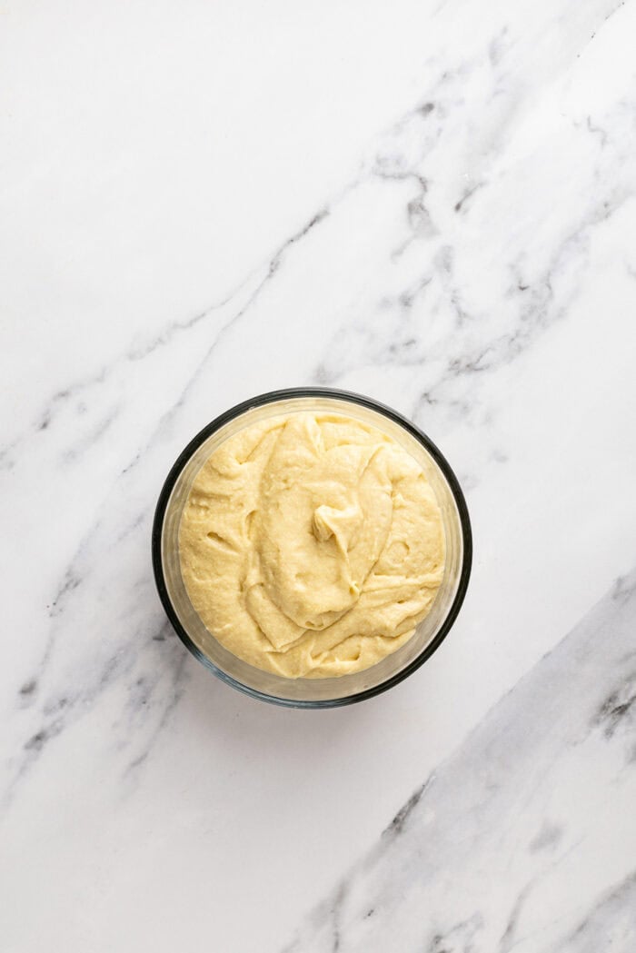 Chocolate and vanilla cake batter are swirled together, baked, and then layered with chocolate buttercream to create this Marble Cake recipe. Cake batter in a bowl