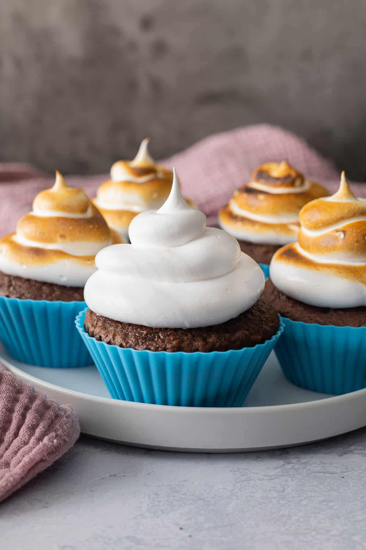 A plate of cupcakes topped with marshmallow frosting