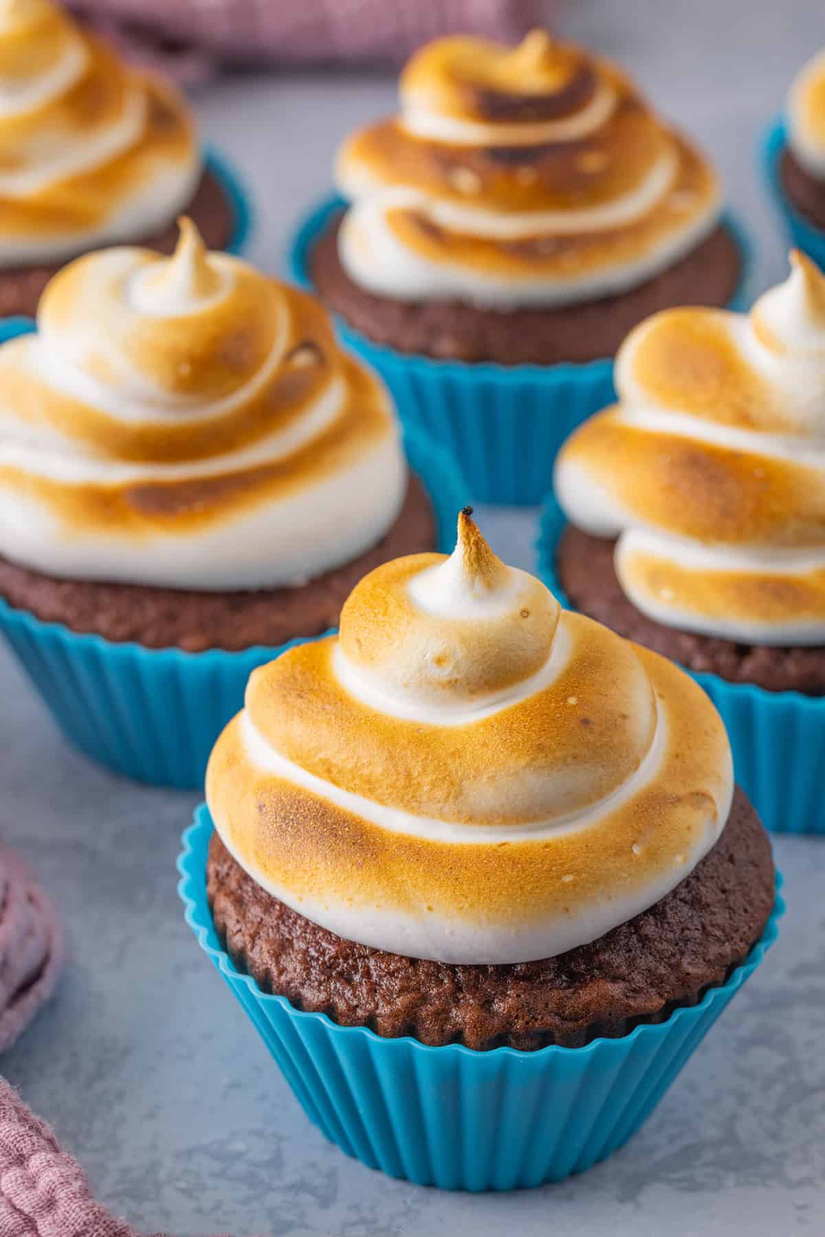 Light and fluffy just like a marshmallow, this Marshmallow Frosting recipe takes just 5 ingredients and 10 minutes to prepare. Chocolate cupcakes in blue liners topped with toasted marshmallow frosting