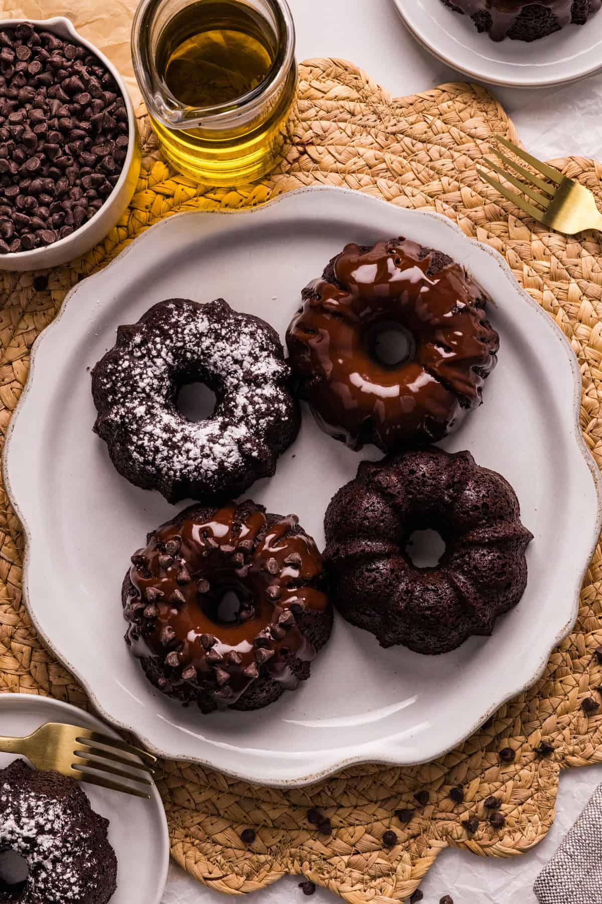 These Mini Chocolate Bundt Cakes offer a rich chocolate flavor and ultra-moist crumb in perfectly portioned, individual cakes. Overhead view of four mini chocolate bundt cakes on a white plate