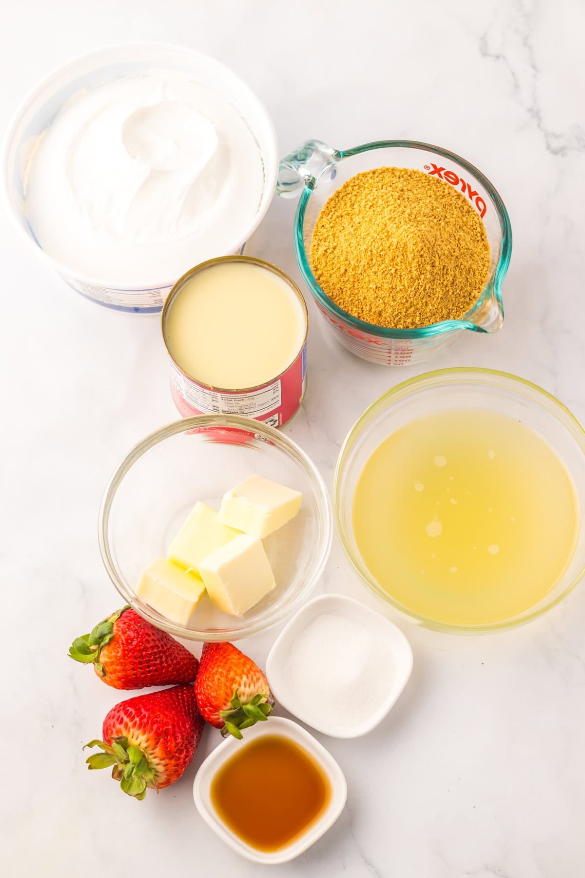 Tangy and fruity, Strawberry Lemonade Pie features layers of creamy lemonade pie filling topped with strawberry swirl. Overhead view of the ingredients needed to make strawberry lemonade pie