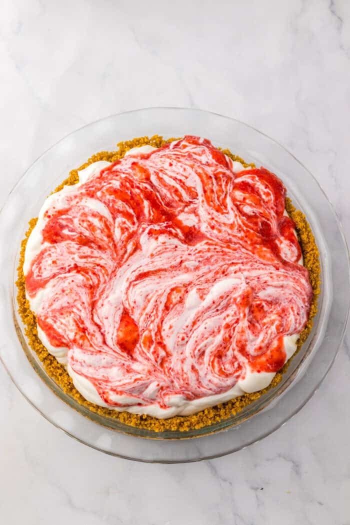 Tangy and fruity, Strawberry Lemonade Pie features layers of creamy lemonade pie filling topped with strawberry swirl. Strawberry filling swirled into lemonade filling in a graham cracker crust