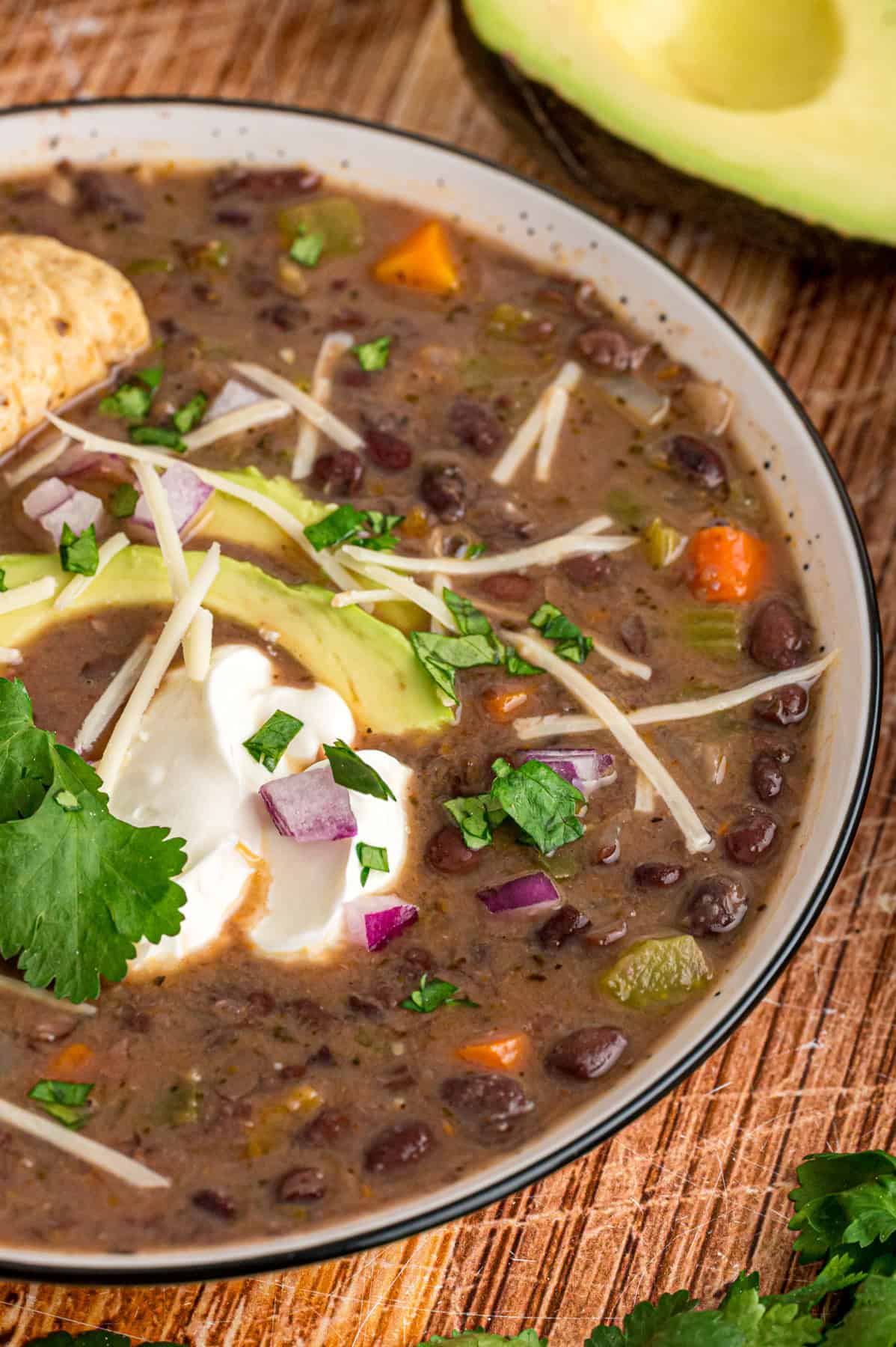 Black beans are simmered with warm, smoky spices and veggies in this Black Bean Soup recipe for an easy vegetarian dinner. A bowl of black bean soup