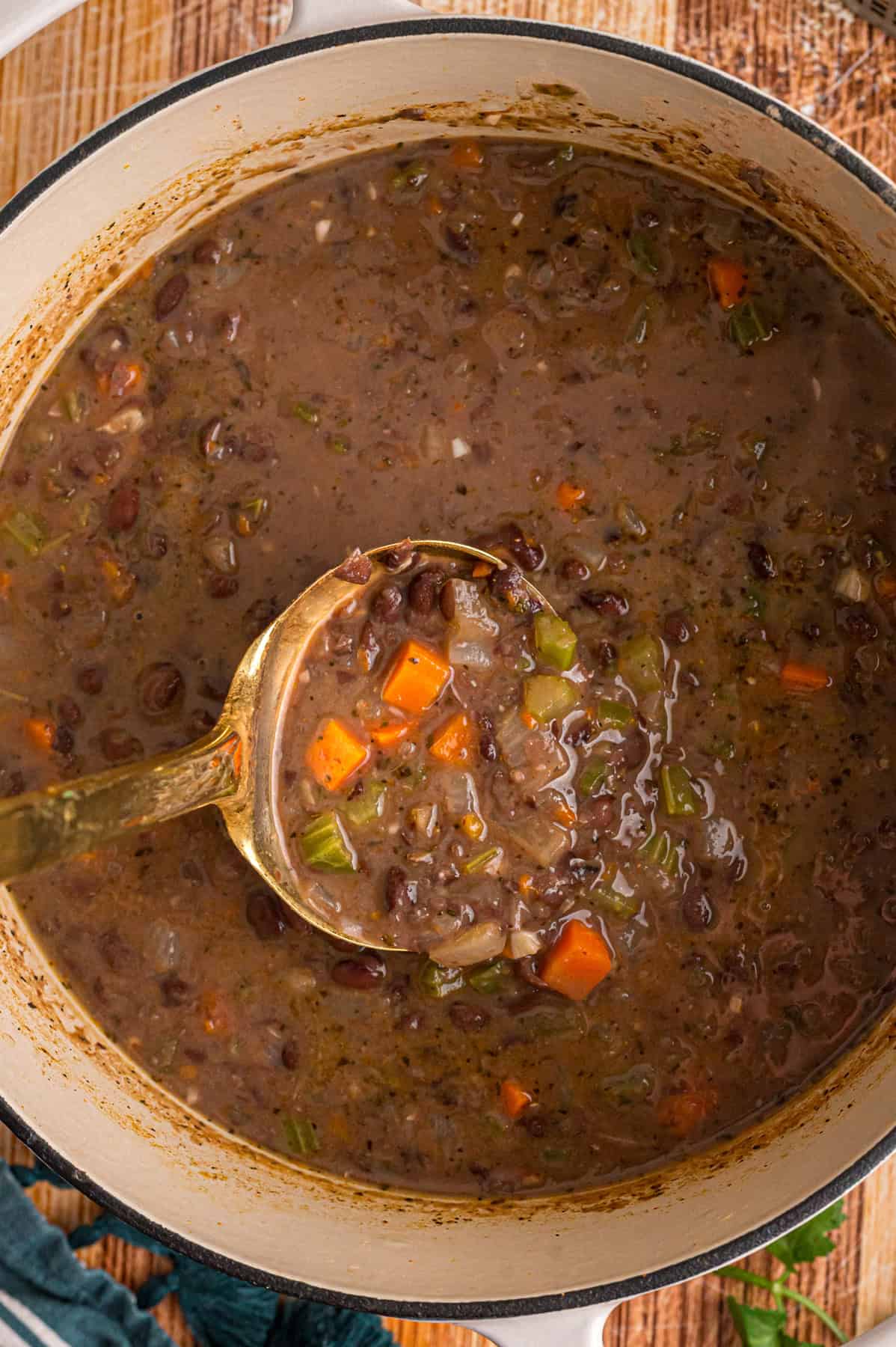 Black beans are simmered with warm, smoky spices and veggies in this Black Bean Soup recipe for an easy vegetarian dinner. A ladle in a pot of black bean soup