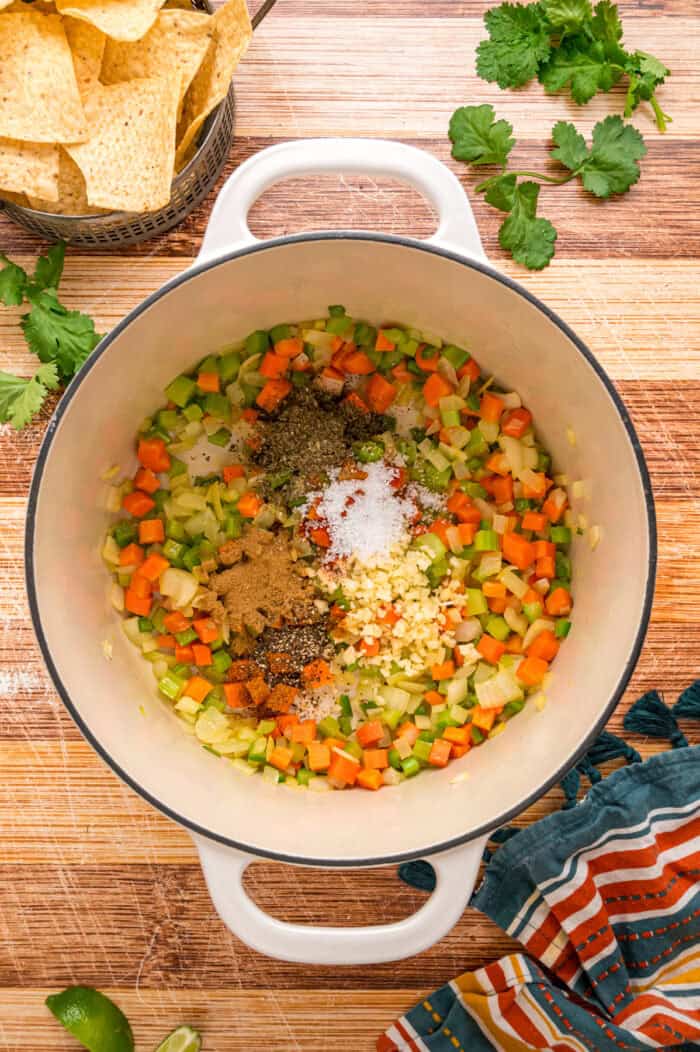 Black beans are simmered with warm, smoky spices and veggies in this Black Bean Soup recipe for an easy vegetarian dinner. Spices added to sauteed veggies