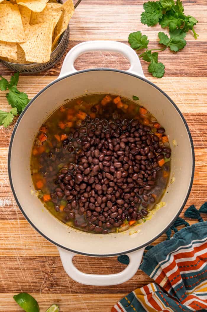 Black beans are simmered with warm, smoky spices and veggies in this Black Bean Soup recipe for an easy vegetarian dinner. Black beans added to the veggies