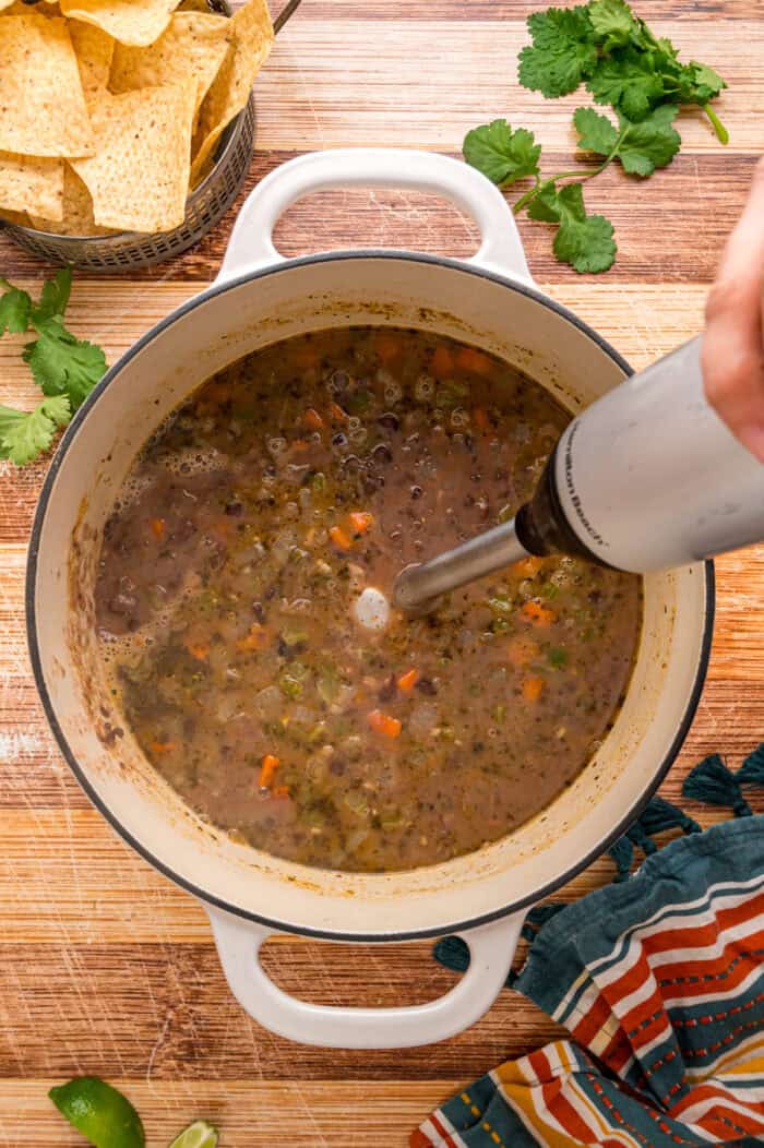 Black beans are simmered with warm, smoky spices and veggies in this Black Bean Soup recipe for an easy vegetarian dinner. An immersion blending in a pot of black bean soup