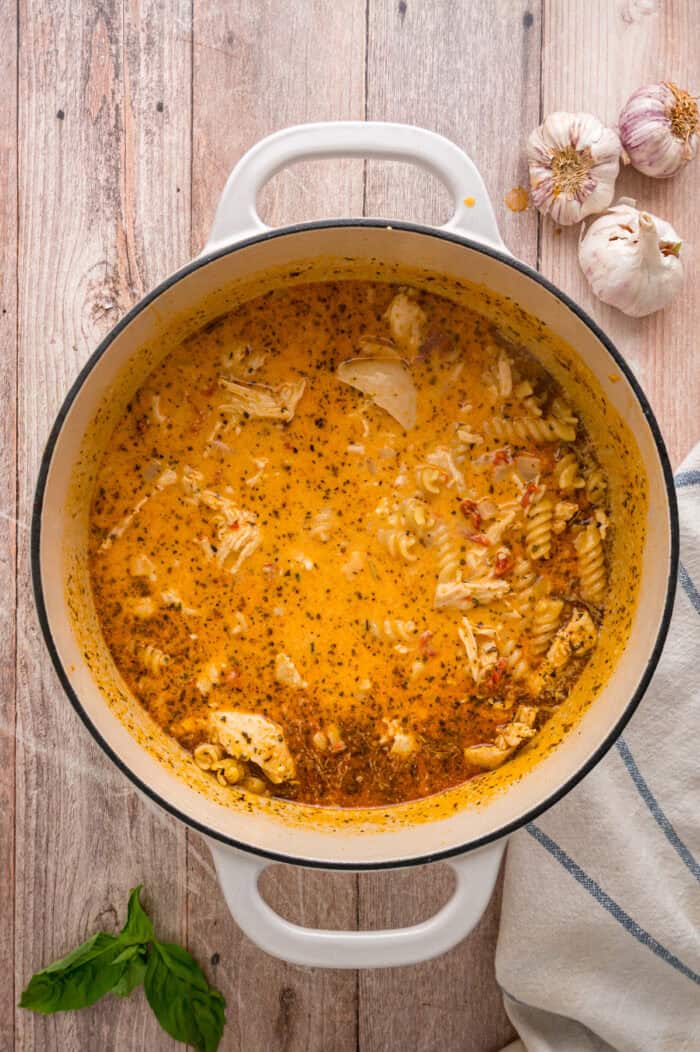Shredded chicken warming in the creamy tomato broth