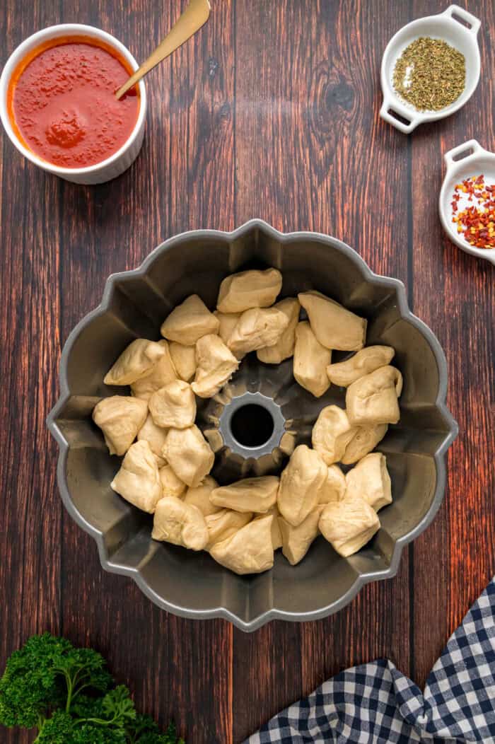 Made with biscuits, mozzarella cheese, and pepperoni, Pizza Pull Apart Bread is both easy to make and fun to eat. Pieces of biscuit dough in a bundt pan