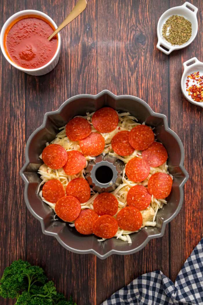 Made with biscuits, mozzarella cheese, and pepperoni, Pizza Pull Apart Bread is both easy to make and fun to eat. Mozzarella cheese and pepperoni on biscuit dough in a bundt pan