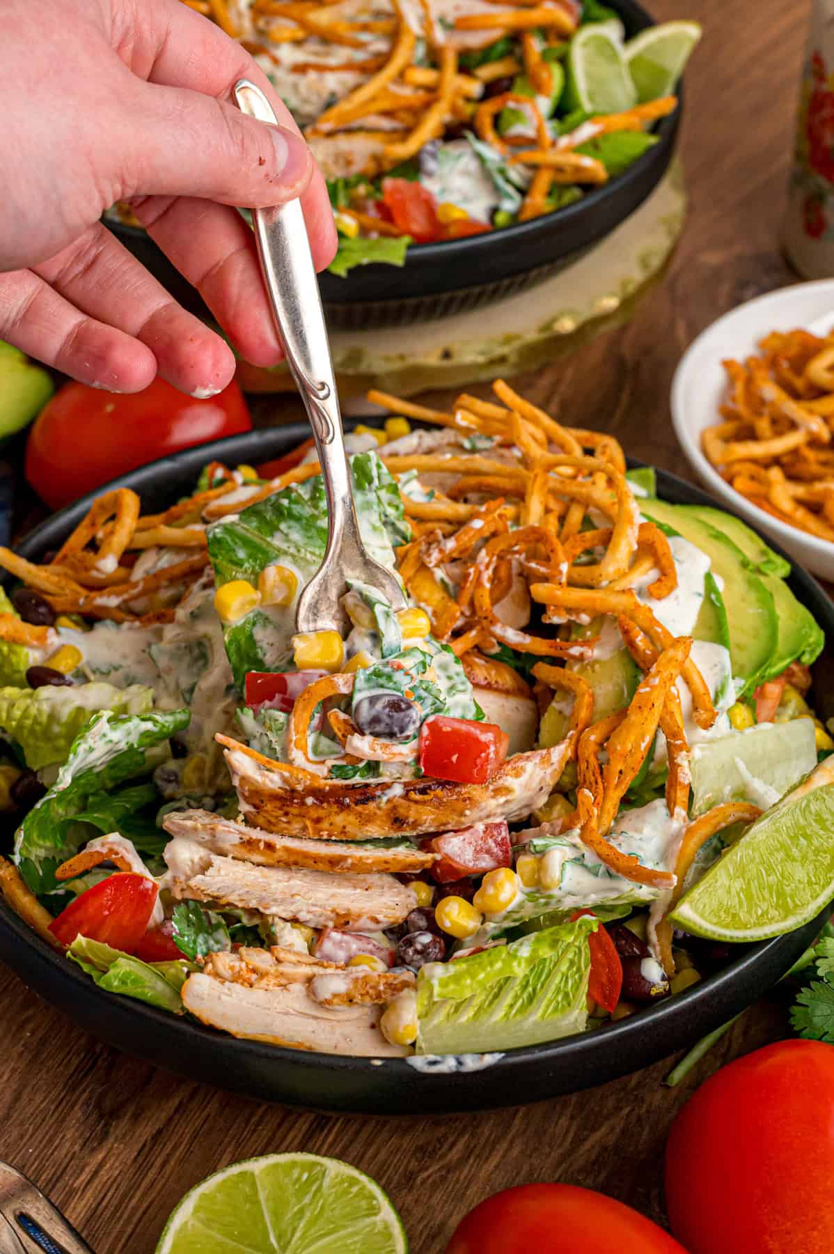 This Southwest Chicken Salad features seasoned chicken, fresh veggies, and a salsa verde dressing over crispy lettuce. Quick & easy! A fork in a bowl of southwest chicken salad