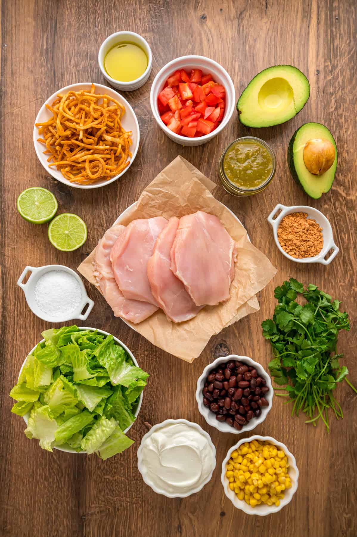 This Southwest Chicken Salad features seasoned chicken, fresh veggies, and a salsa verde dressing over crispy lettuce. Quick & easy! Overhead view of ingredients needed to make southwest chicken salad