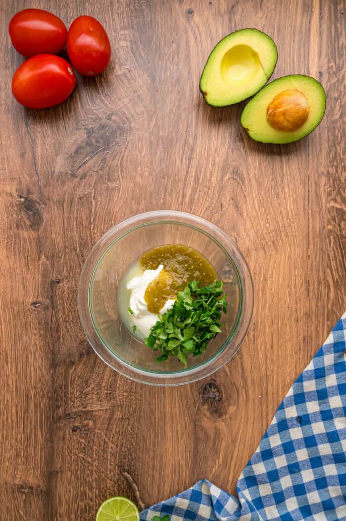 This Southwest Chicken Salad features seasoned chicken, fresh veggies, and a salsa verde dressing over crispy lettuce. Quick & easy! Salsa verde, sour cream, and cilantro in a bowl