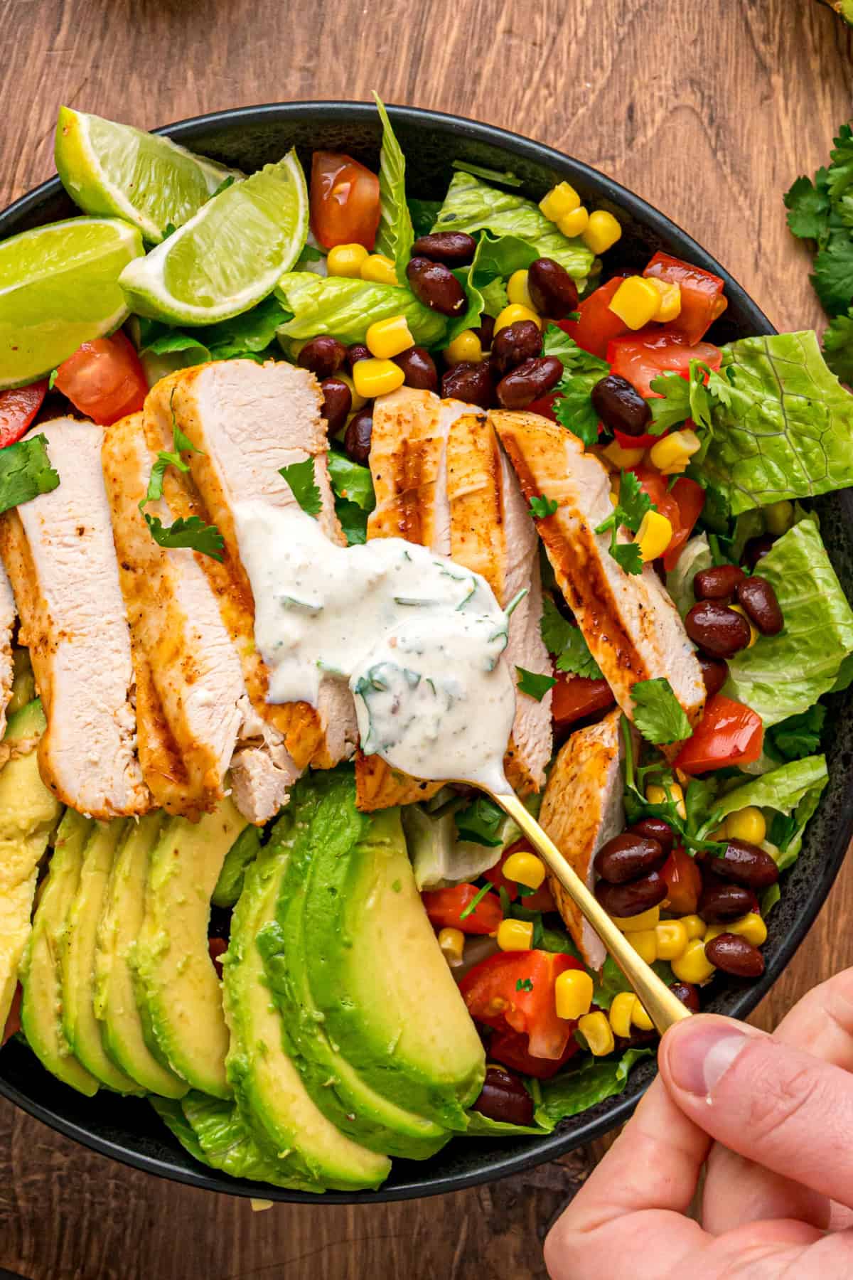This Southwest Chicken Salad features seasoned chicken, fresh veggies, and a salsa verde dressing over crispy lettuce. Quick & easy! Southwest Chicken Salad with dressing being spooned over the top