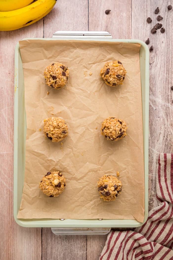 Made with just 3 ingredients in less than 25 minutes, these Banana Oatmeal Cookies are quick, easy, and so yummy. Balls of banana oatmeal cookie dough on a baking sheet