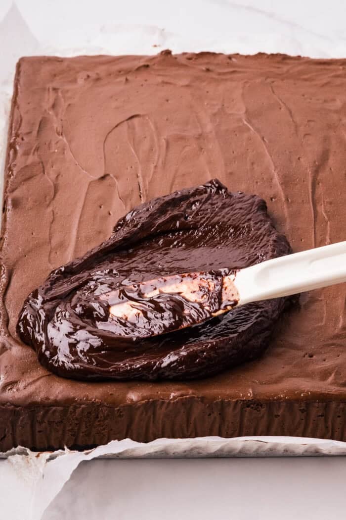 Chocolate Cheesecake Bars are ultra-decadent with three layers of chocolate. Easy to make & great for sharing! Spreading chocolate ganache on chocolate cheesecake