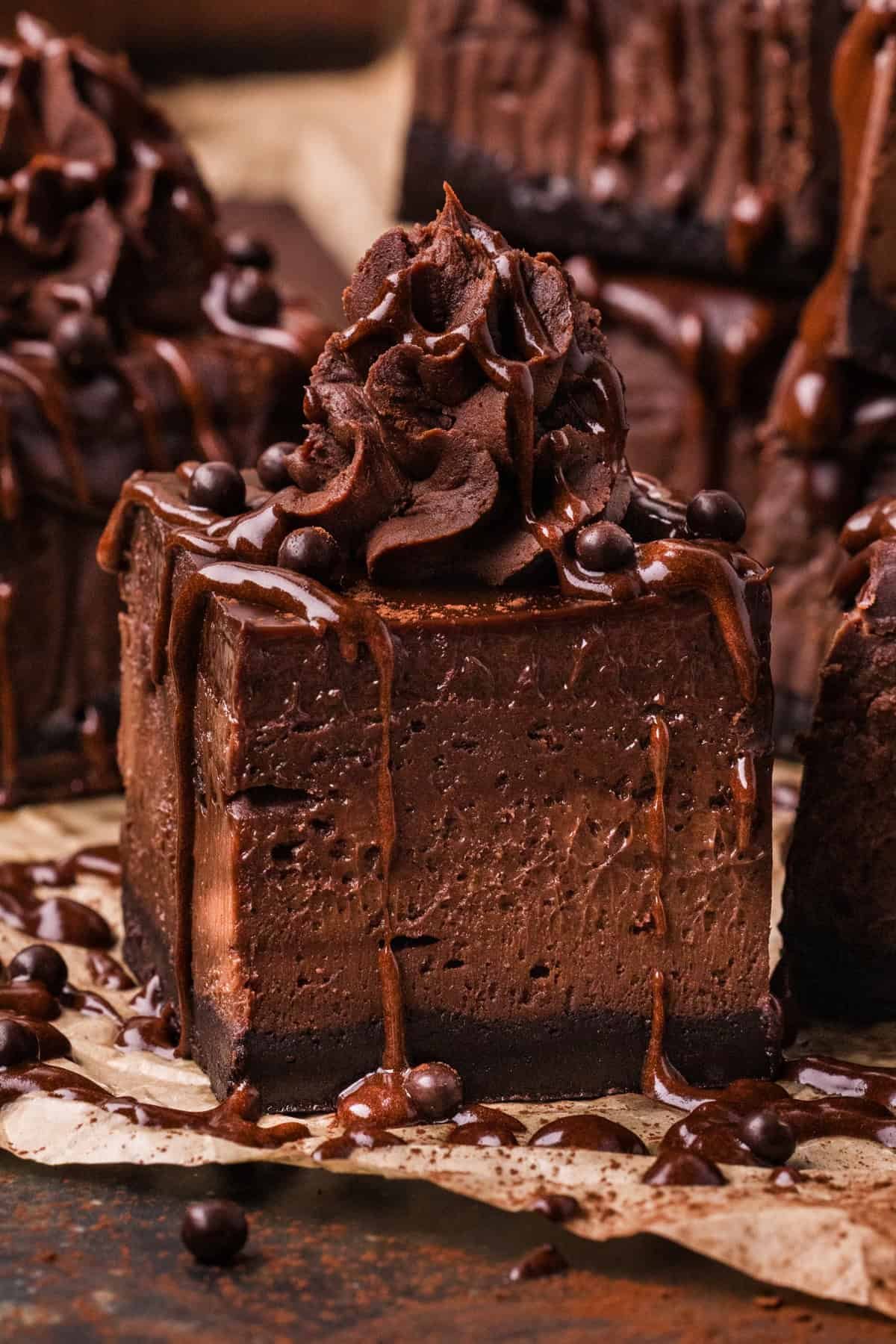 Chocolate Cheesecake Bars are ultra-decadent with three layers of chocolate. Easy to make & great for sharing! A chocolate cheesecake bar with whipped ganache and chocolate drizzle