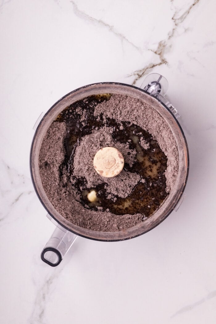 Chocolate Cheesecake Bars are ultra-decadent with three layers of chocolate. Easy to make & great for sharing! Melted butter drizzled over chocolate crumbs in a food processor