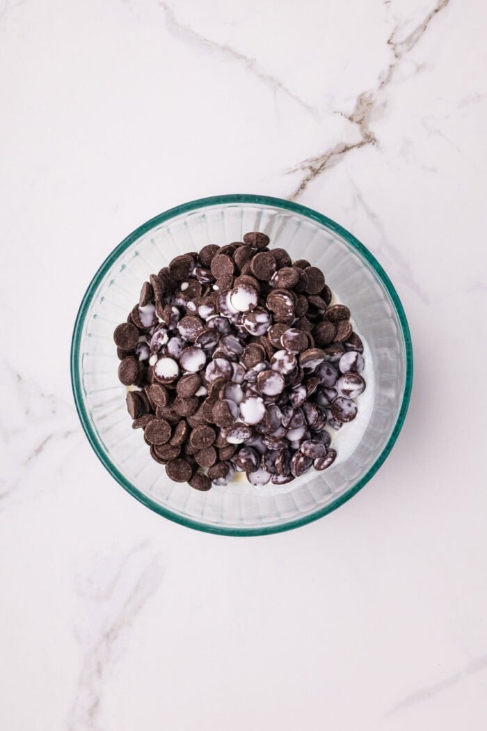 Chocolate Cheesecake Bars are ultra-decadent with three layers of chocolate. Easy to make & great for sharing! Heavy cream and chocolate chips in a bowl