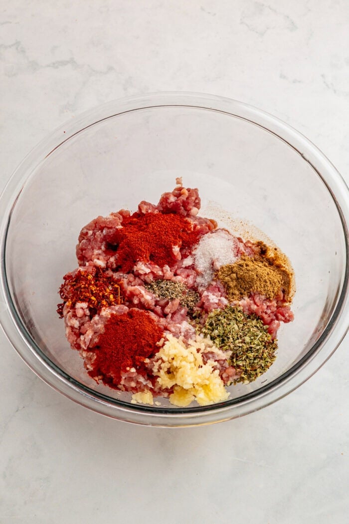 Ground pork, spices, and garlic in a bowl