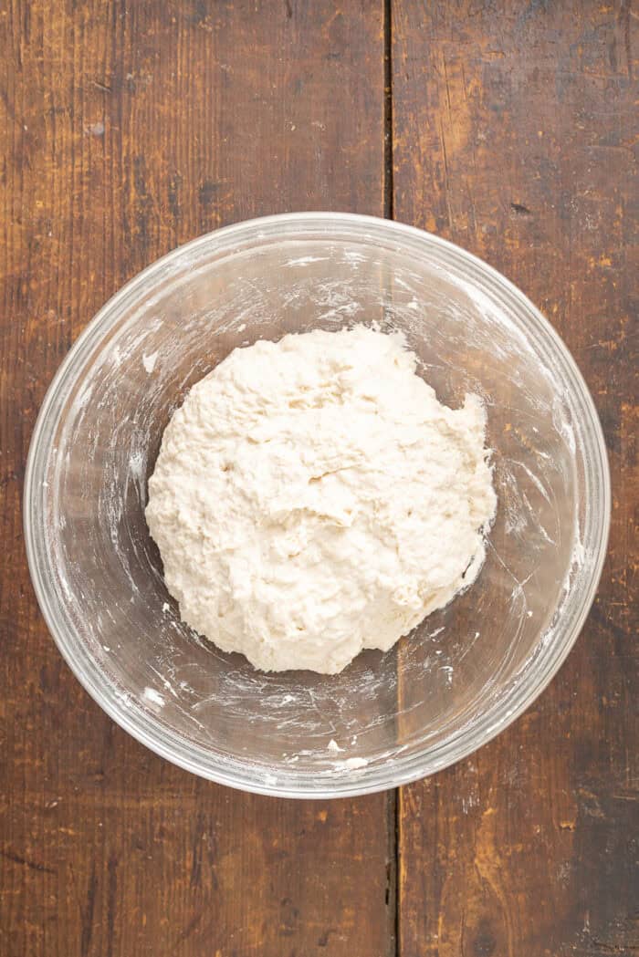 Make a crusty artisan loaf of bread at home with just 10 minutes of prep with this No Knead Dutch Oven Bread recipe. Just 4 ingredients! Dry ingredients added to a bowl of yeast and water