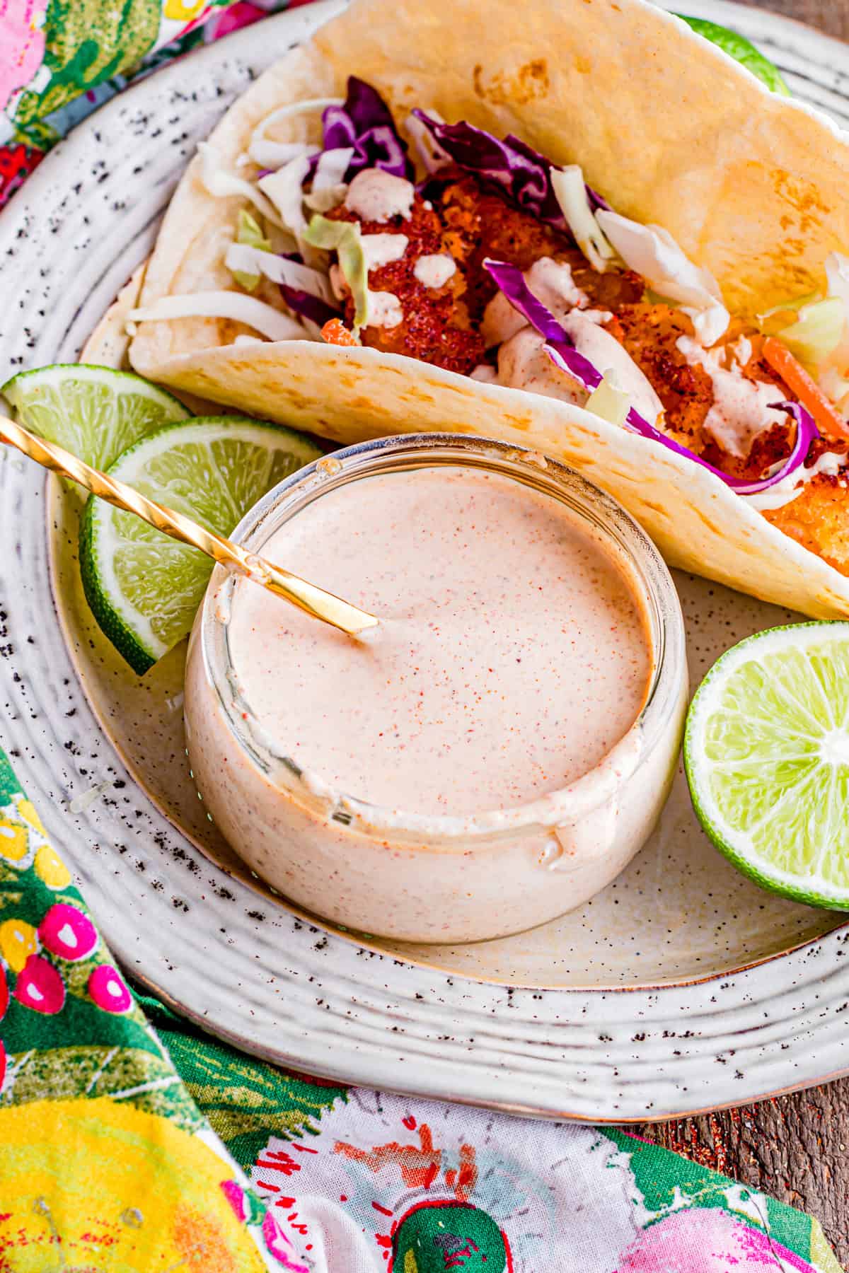 A jar of fish taco sauce on a plate with a fish taco