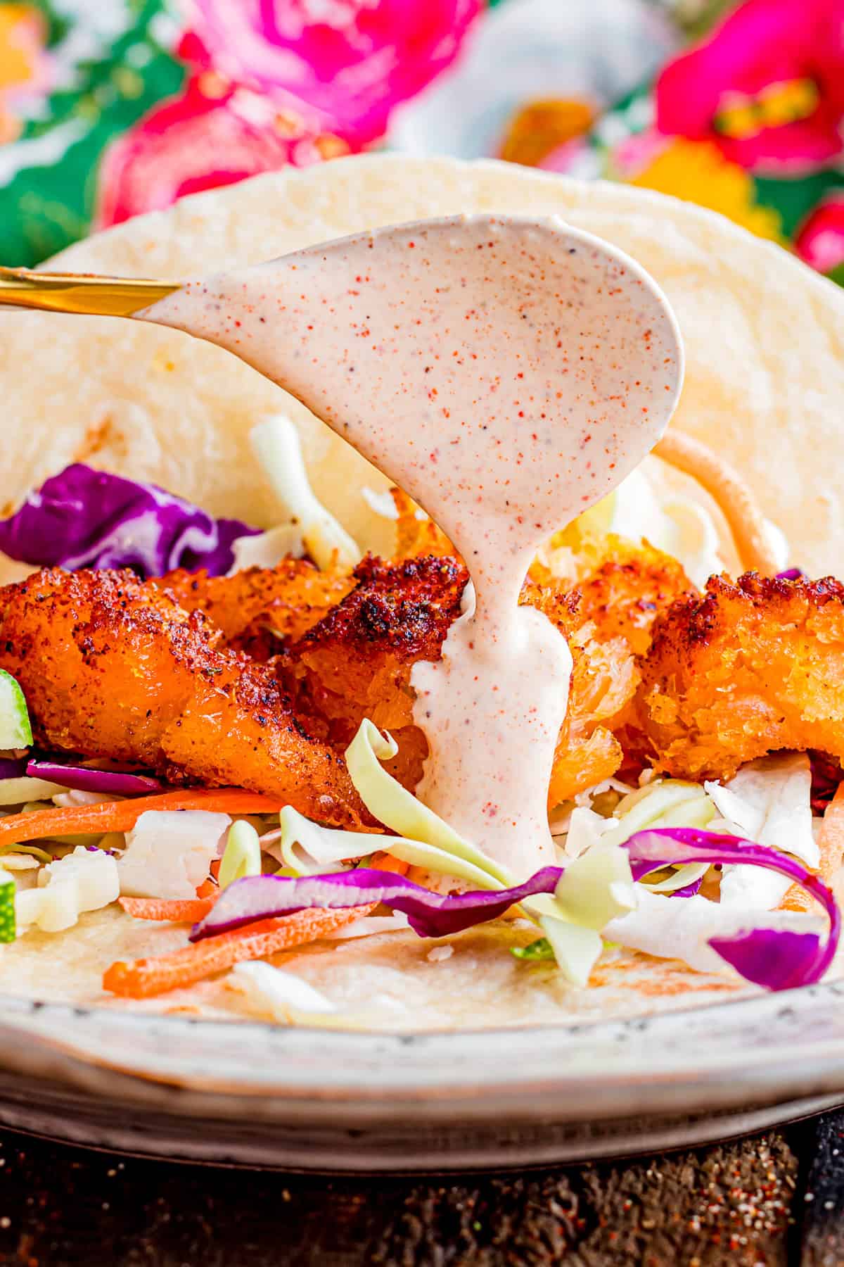 Spooning fish taco sauce over a fish taco