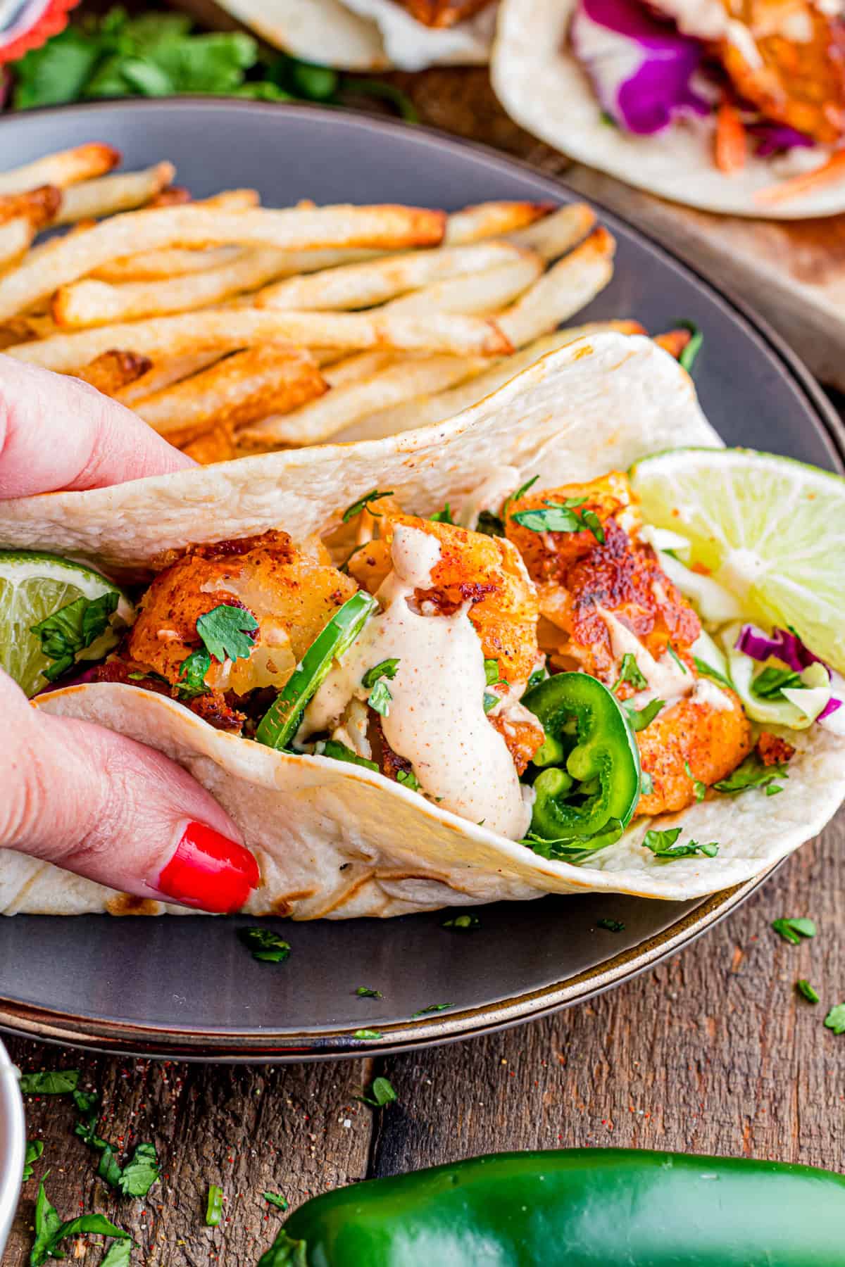 Topped with tangy fish taco sauce, these Blackened Fish Tacos are bold, flavorful, and ready in under 20 minutes. A hand picking up a fish taco