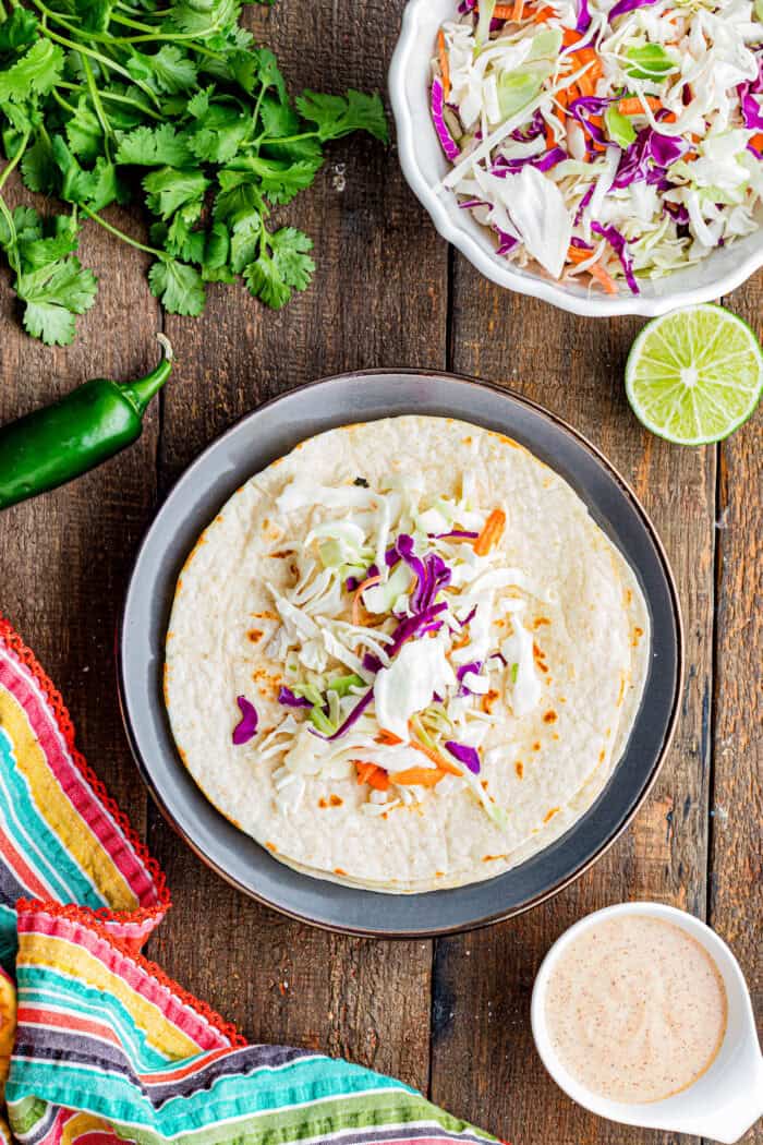 Topped with tangy fish taco sauce, these Blackened Fish Tacos are bold, flavorful, and ready in under 20 minutes. Coleslaw mix on a flour tortilla