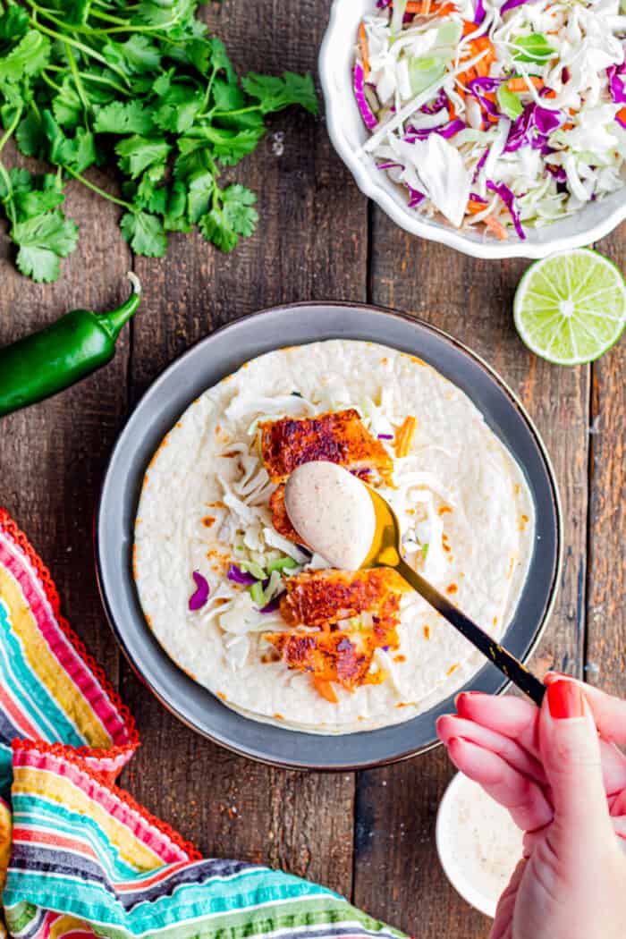 Topped with tangy fish taco sauce, these Blackened Fish Tacos are bold, flavorful, and ready in under 20 minutes. Spooning fish taco sauce over blackened fish
