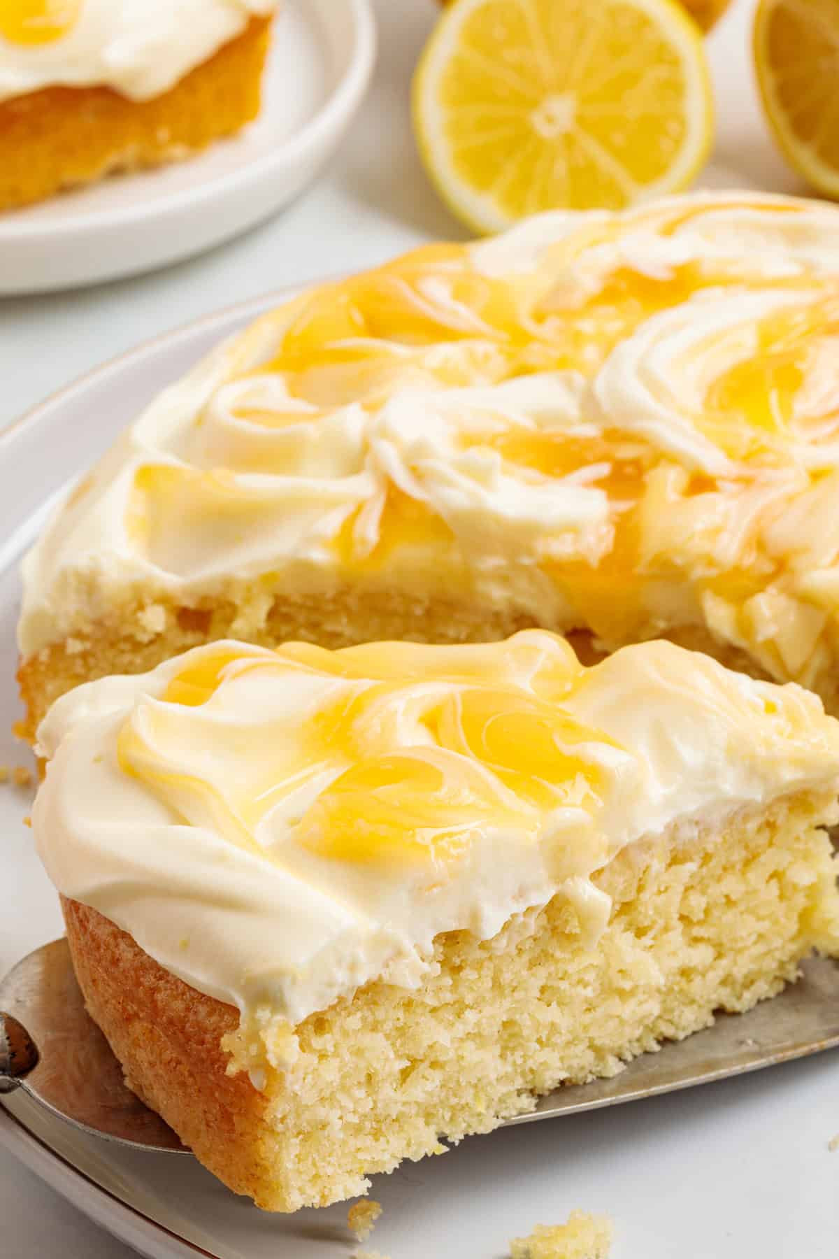 This Limoncello Mascarpone Cake begins with a moist lemon cake topped with limoncello syrup, mascarpone cream, and lemon curd. Side view of a sliced Limoncello Mascarpone Cake