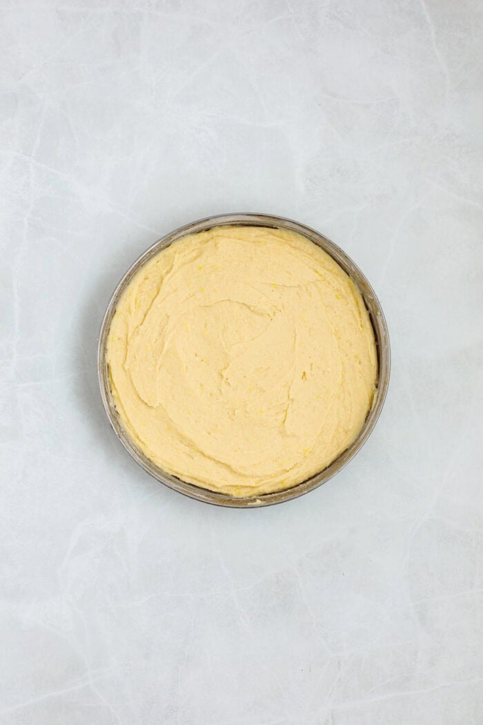 This Limoncello Mascarpone Cake begins with a moist lemon cake topped with limoncello syrup, mascarpone cream, and lemon curd. Lemon cake batter in a circle pan