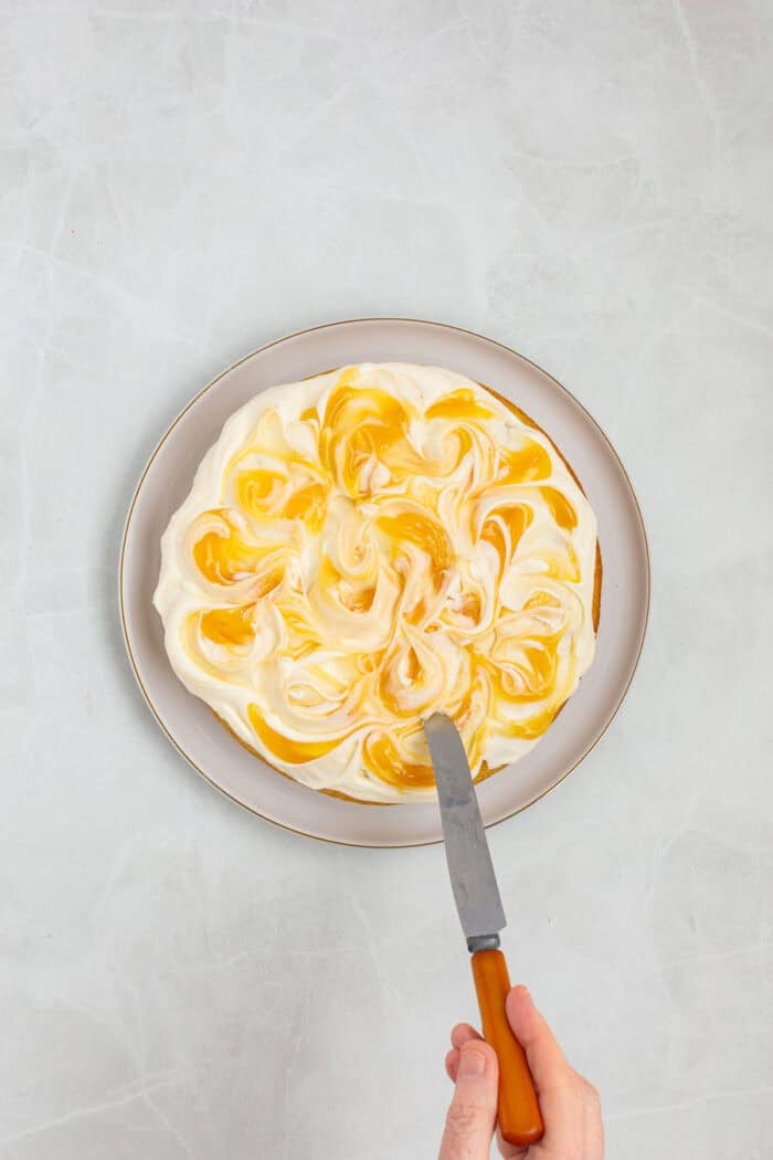 This Limoncello Mascarpone Cake begins with a moist lemon cake topped with limoncello syrup, mascarpone cream, and lemon curd. Lemon curd on mascarpone cream on a cake
