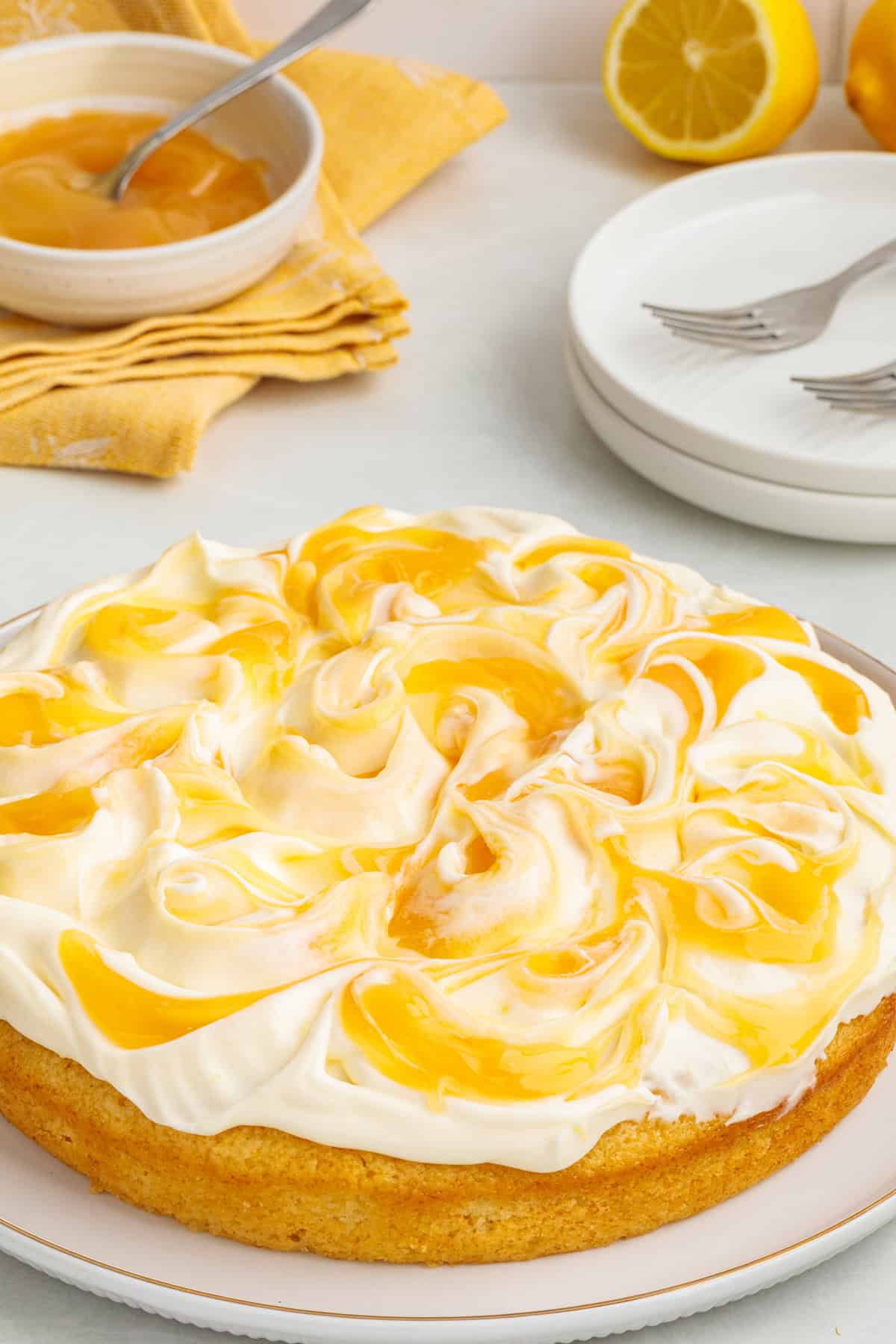This Limoncello Mascarpone Cake begins with a moist lemon cake topped with limoncello syrup, mascarpone cream, and lemon curd. Overhead view of Limoncello Mascarpone Cake on a plate