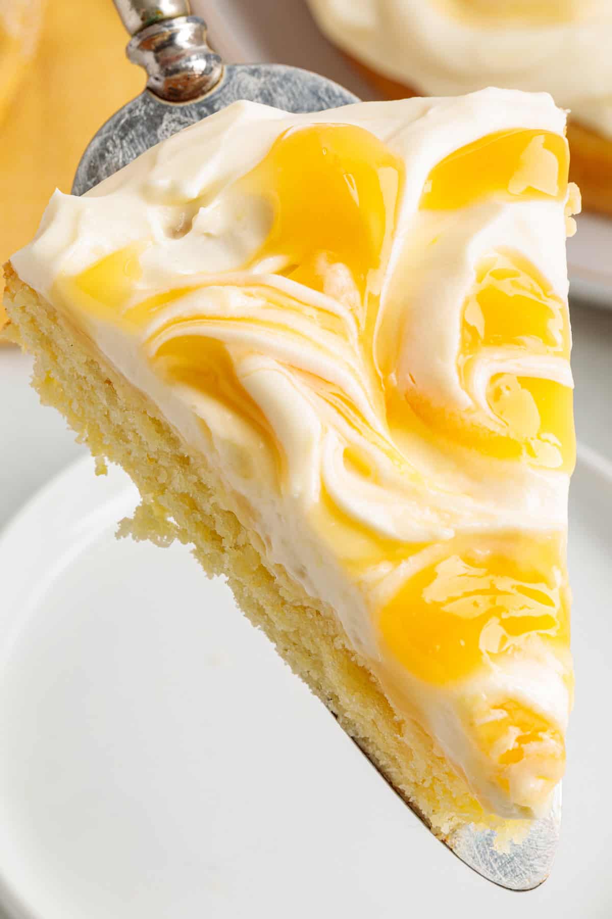 This Limoncello Mascarpone Cake begins with a moist lemon cake topped with limoncello syrup, mascarpone cream, and lemon curd. Serving a slice of Limoncello Mascarpone Cake