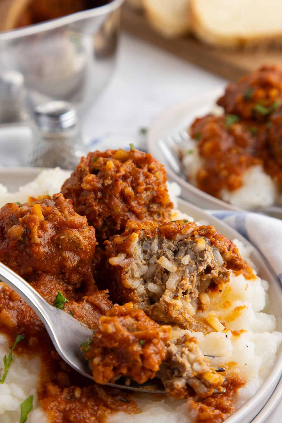 A fork on a plate of porcupine meatballs with mashed potatoes
