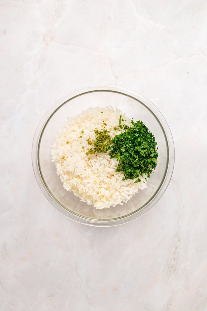 A bed of rice is topped with juicy, lightly charred flank steak, creamy yogurt lime drizzle, and veggies in this Steak Rice Bowl recipe. Rice, lime zest, and cilantro in a bowl