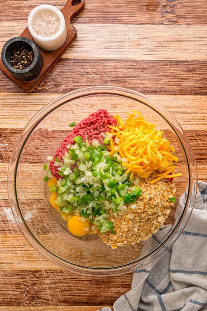 Shredded cheddar, sauteed onions and bell peppers, and Ritz cracker crumbs make this Cracker Barrel Meatloaf extra moist and flavorful. Ground beef, cheese, Ritz cracker crumbs, sauteed veggies, and egg in a bowl