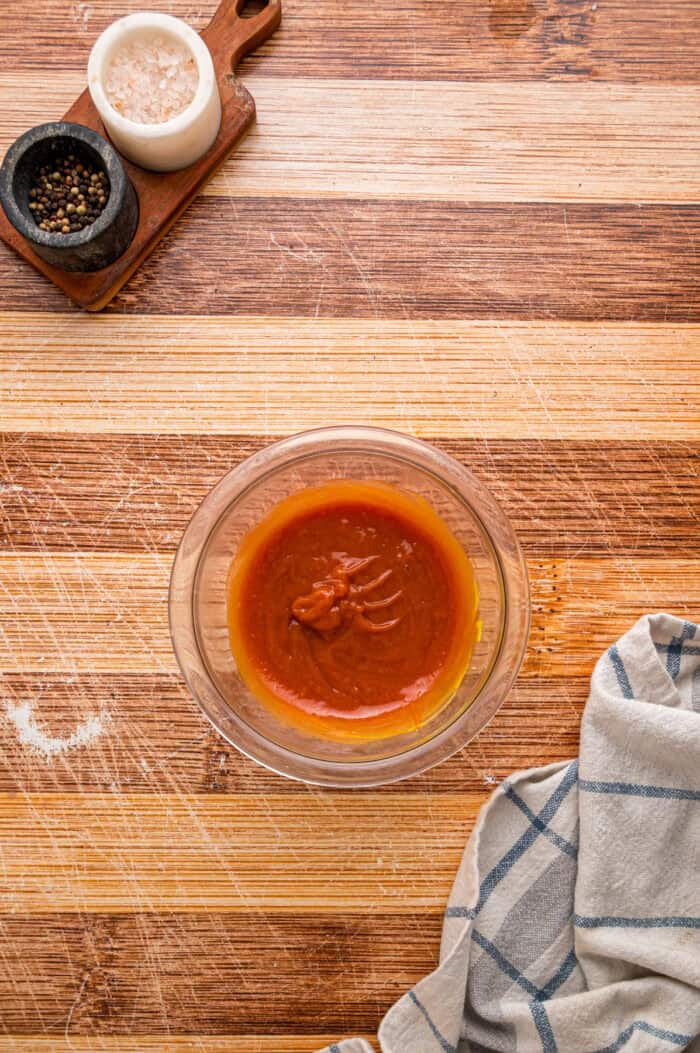Shredded cheddar, sauteed onions and bell peppers, and Ritz cracker crumbs make this Cracker Barrel Meatloaf extra moist and flavorful. Ketchup glaze in a small bowl