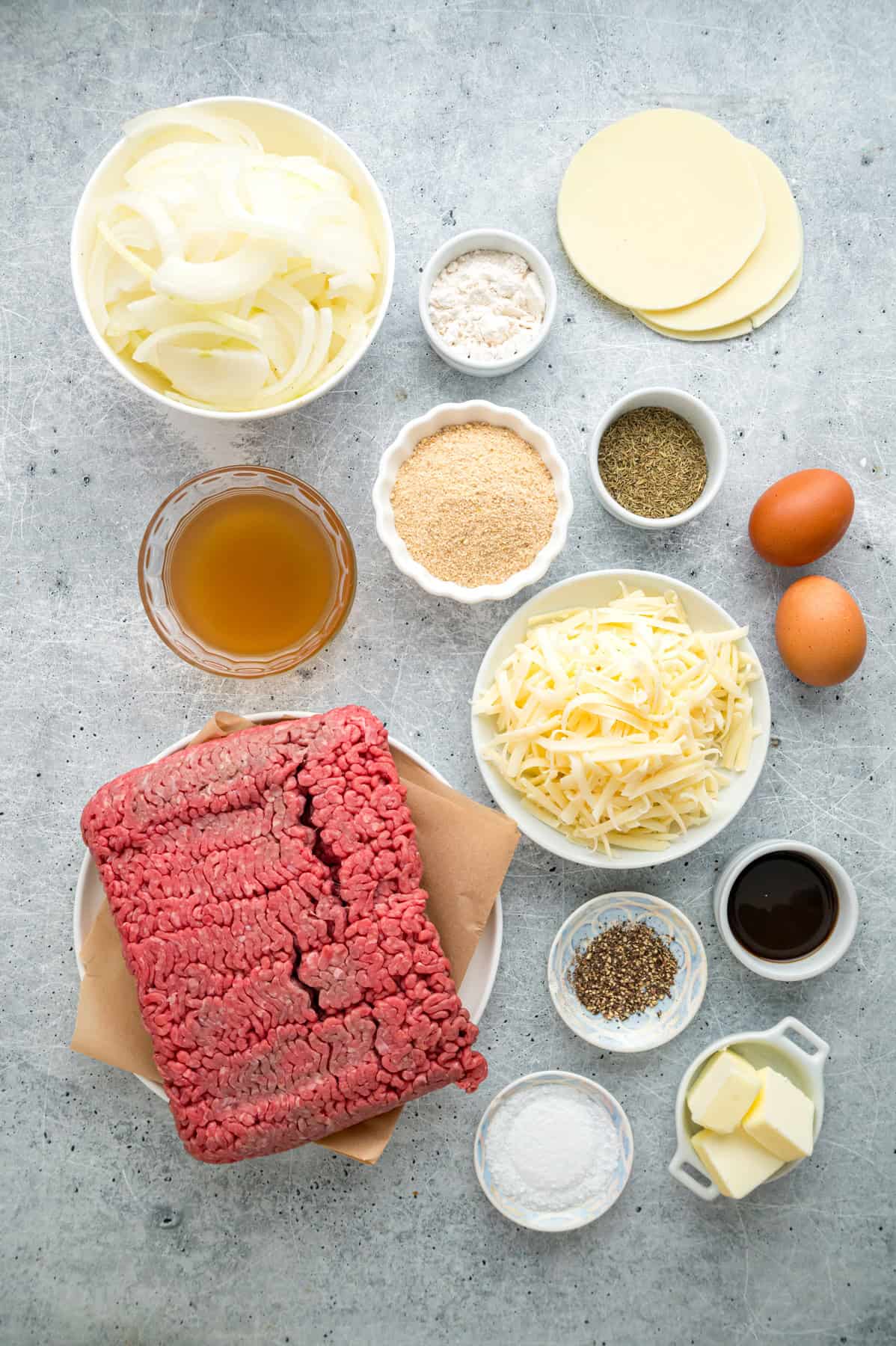 Caramelized onions, a savory onion sauce, and gooey, cheese turn basic meatloaf into an elevated dinner in this French Onion Meatloaf recipe. Overhead view of ingredients needed to make French onion meatloaf
