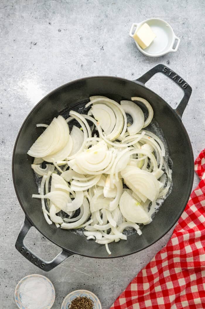 Caramelized onions, a savory onion sauce, and gooey, cheese turn basic meatloaf into an elevated dinner in this French Onion Meatloaf recipe. Sliced onions in a skillet