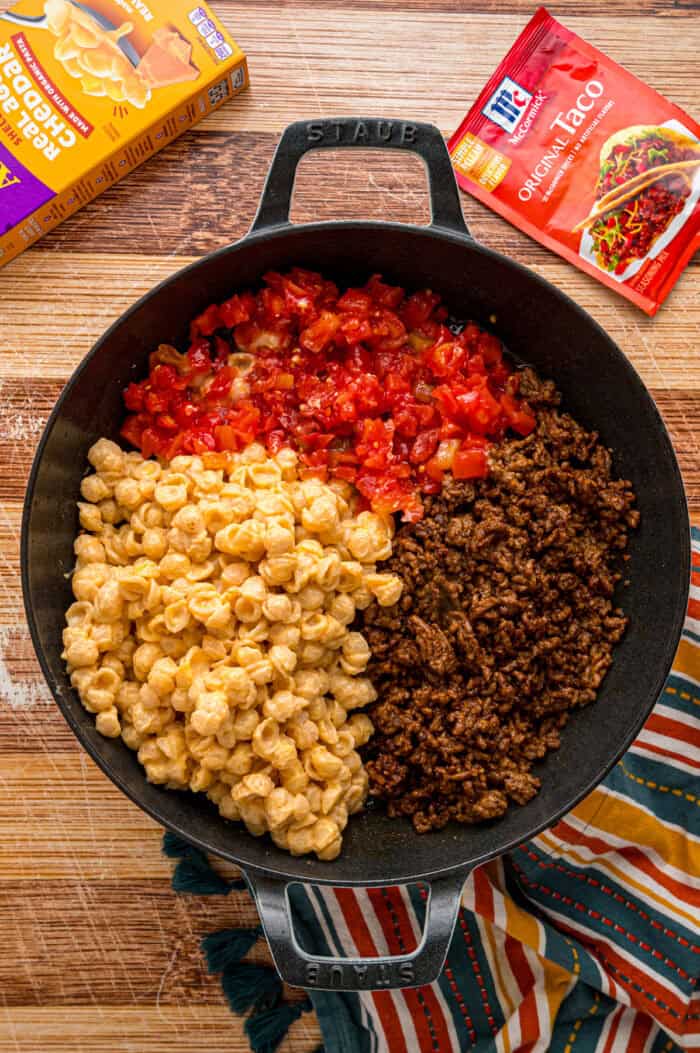 Seasoned ground beef, Rotel, and mac and cheese in a skillet