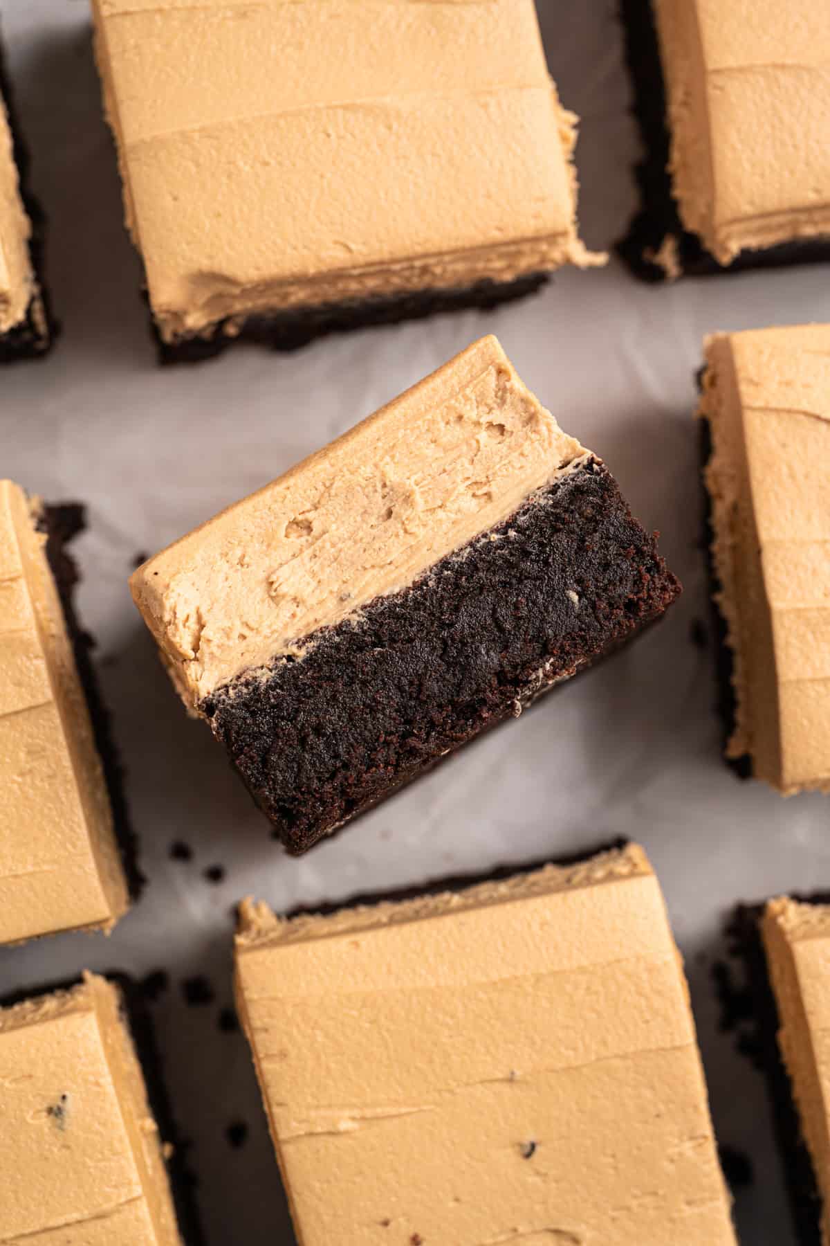 Espresso Brownies feature fudgy, dense chocolate brownies with a hint of espresso, topped with a layer of espresso buttercream frosting. Overhead view of espresso brownies, one on its side to show the layers