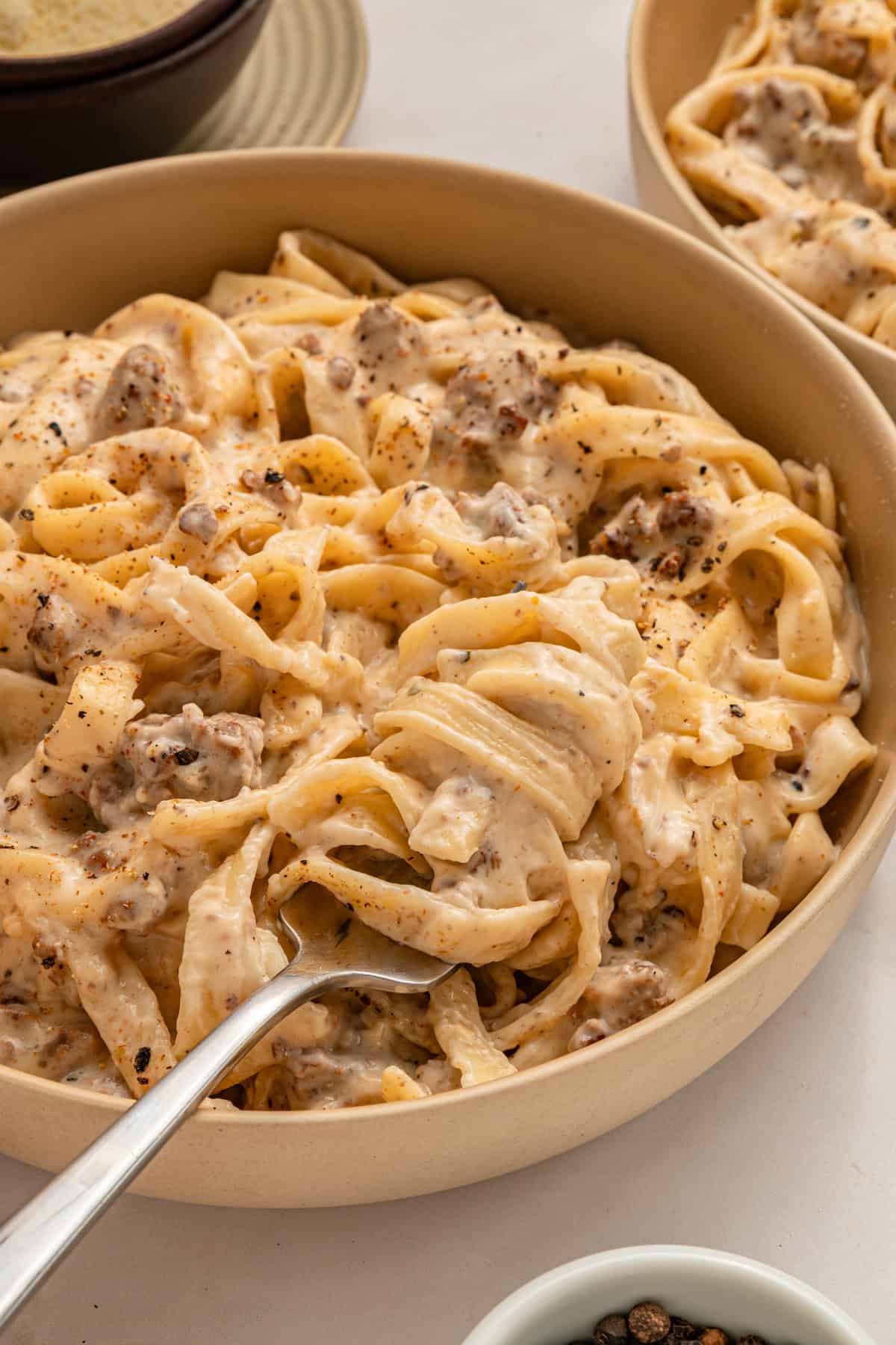 A fork in a bowl of ground beef alfredo