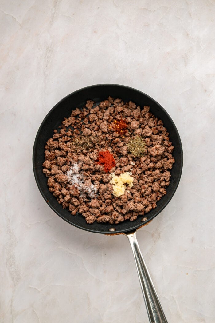 Spices added to ground beef in a skillet