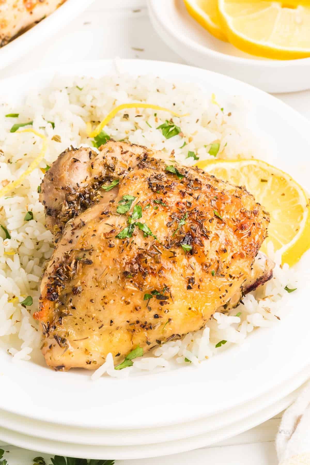 A lemon chicken thigh on a plate with rice