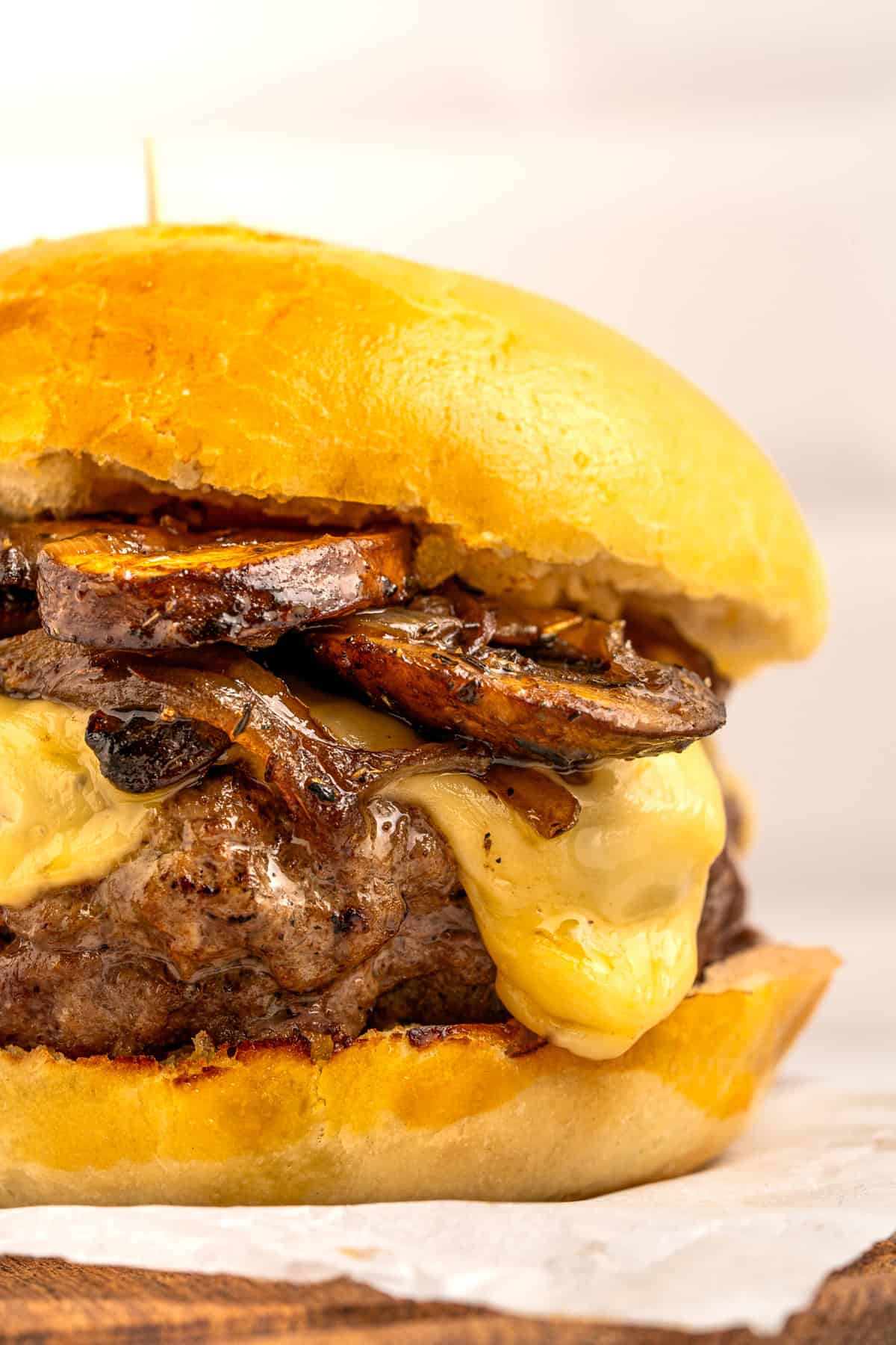 Juicy beef burgers are topped with slices of melty Swiss cheese and savory sauteed mushrooms in this Mushroom Swiss Burger recipe. Close up of a mushroom Swiss burger to show the melty cheese