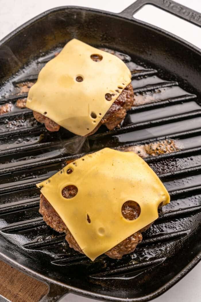 Juicy beef burgers are topped with slices of melty Swiss cheese and savory sauteed mushrooms in this Mushroom Swiss Burger recipe. Slices of Swiss cheese on burgers
