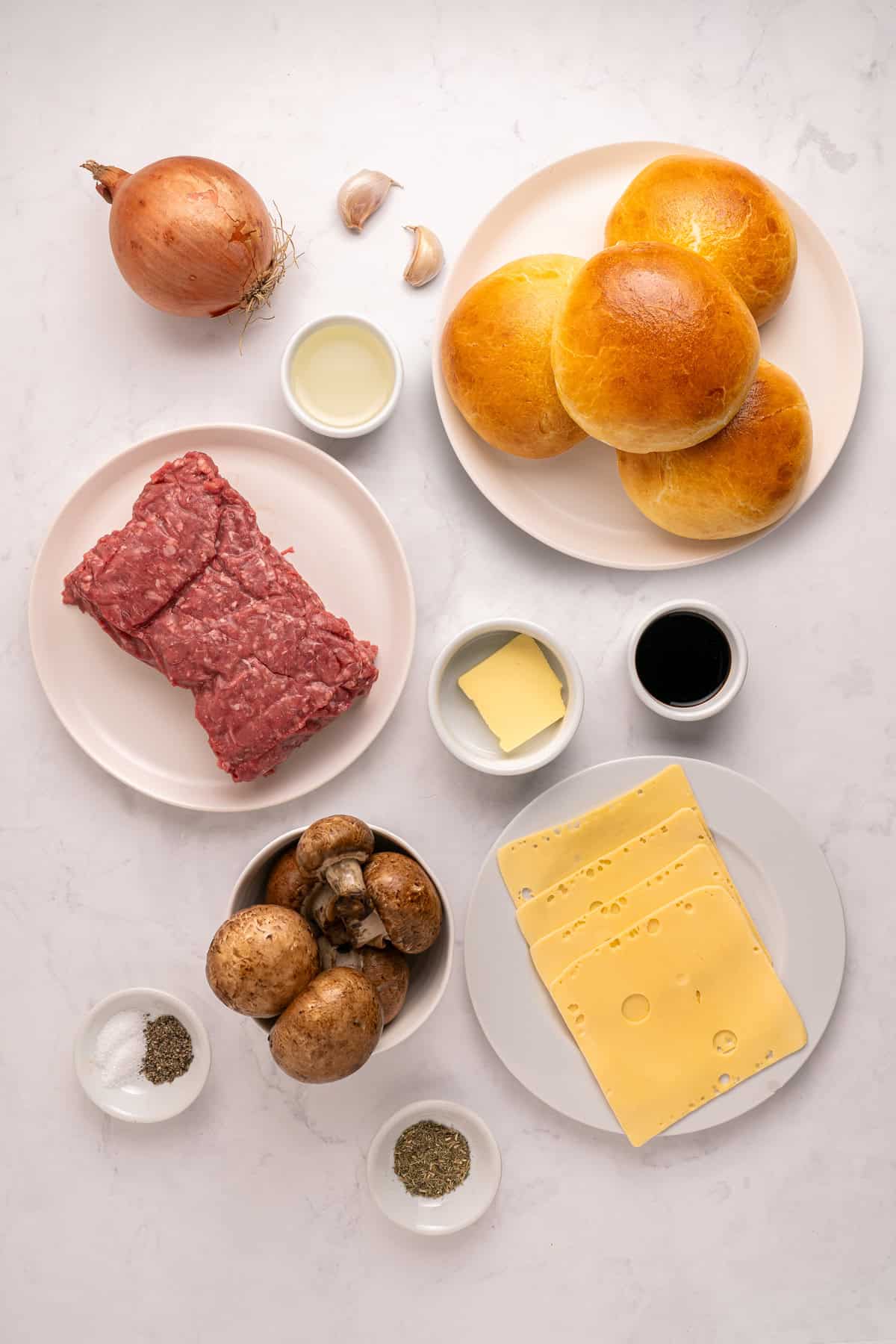 Juicy beef burgers are topped with slices of melty Swiss cheese and savory sauteed mushrooms in this Mushroom Swiss Burger recipe. Overhead view of ingredients needed to make mushroom swiss burgers