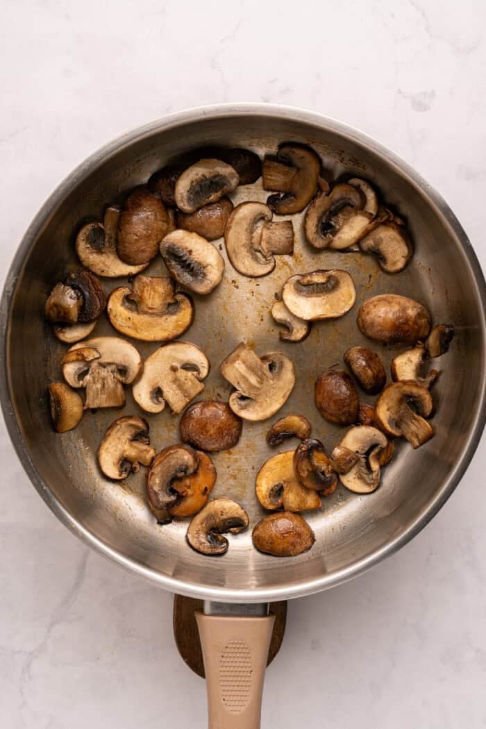 Juicy beef burgers are topped with slices of melty Swiss cheese and savory sauteed mushrooms in this Mushroom Swiss Burger recipe. Sliced mushrooms in a pan